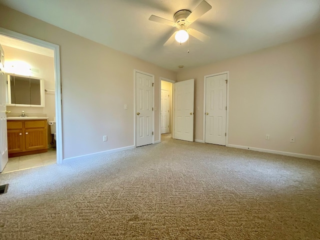 unfurnished bedroom with a sink, connected bathroom, light carpet, baseboards, and visible vents