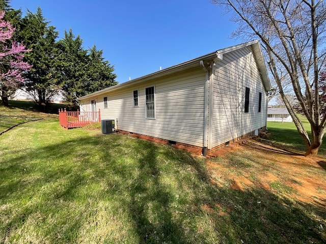 view of side of home with cooling unit, a lawn, and crawl space