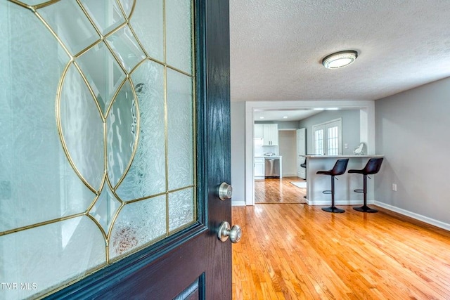 entryway featuring wood finished floors, baseboards, and a textured ceiling