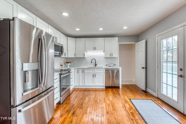 kitchen featuring stainless steel appliances, a sink, light countertops, a textured ceiling, and white cabinets