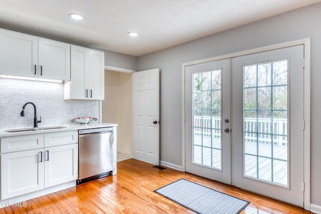 kitchen featuring dishwasher, a sink, backsplash, light wood finished floors, and recessed lighting