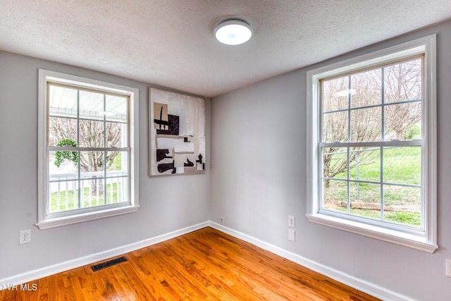 unfurnished room featuring baseboards, wood finished floors, and a textured ceiling