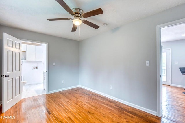 unfurnished room with light wood finished floors, a ceiling fan, baseboards, and a smoke detector