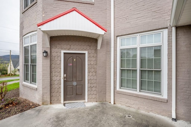 view of exterior entry featuring brick siding