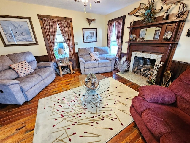 living room featuring wooden walls, a high end fireplace, wood finished floors, and wainscoting