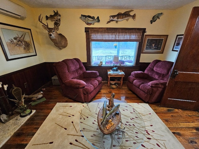 living room with wainscoting, wood walls, a textured ceiling, wood finished floors, and a wall mounted air conditioner