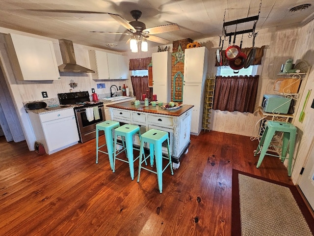 kitchen featuring visible vents, white cabinetry, stainless steel electric range, freestanding refrigerator, and wall chimney exhaust hood