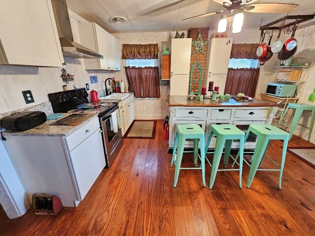 kitchen featuring visible vents, electric range oven, wood finished floors, white cabinetry, and a sink