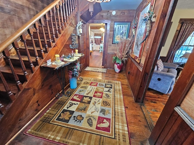 hall with stairway, wood-type flooring, and wooden walls