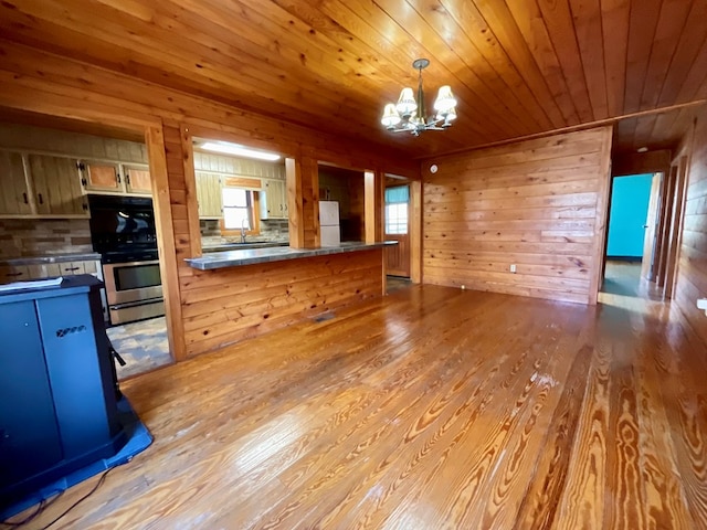 kitchen featuring dark countertops, freestanding refrigerator, light wood-style floors, an inviting chandelier, and wooden ceiling