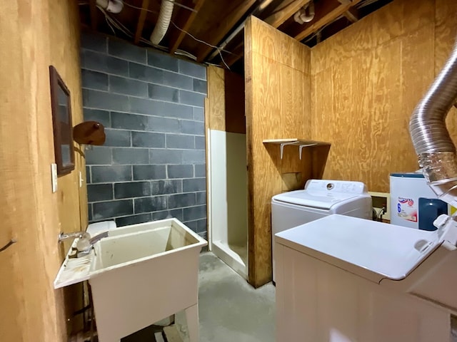 laundry area with water heater, laundry area, independent washer and dryer, concrete block wall, and a sink