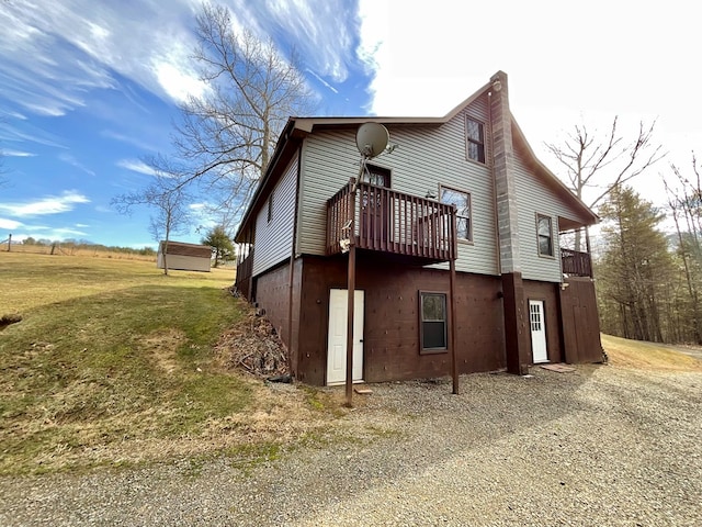 view of side of home featuring a wooden deck, a lawn, and a chimney