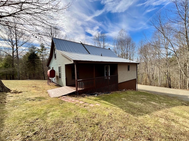 back of house featuring a yard, a porch, and metal roof