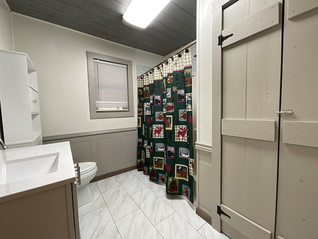 full bath with toilet, marble finish floor, curtained shower, a decorative wall, and vanity