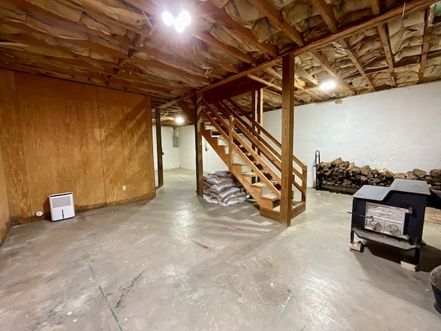 unfinished below grade area featuring stairs and a wood stove