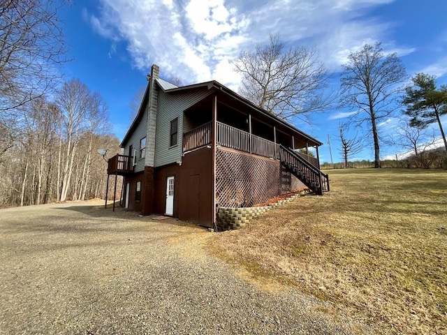 view of home's exterior featuring a lawn, driveway, a chimney, and stairs