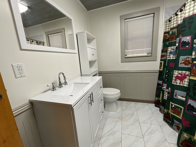 bathroom with vanity, a wainscoted wall, a decorative wall, toilet, and marble finish floor