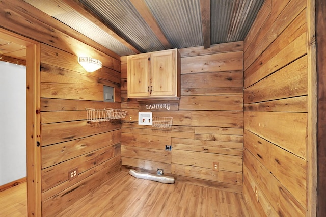 clothes washing area featuring wood walls, cabinets, washer hookup, and light hardwood / wood-style flooring