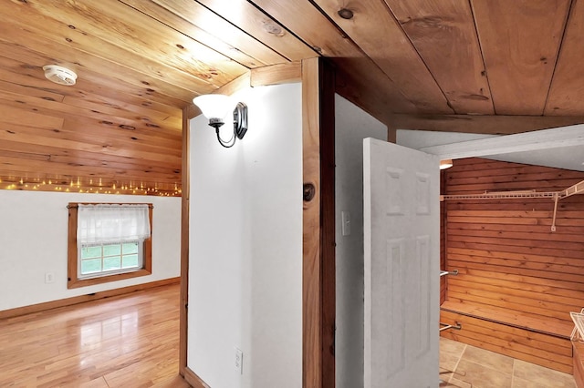 hallway with wooden walls, wooden ceiling, and lofted ceiling