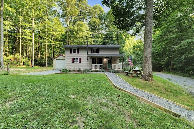 view of property featuring covered porch, an outdoor structure, a garage, and a front lawn