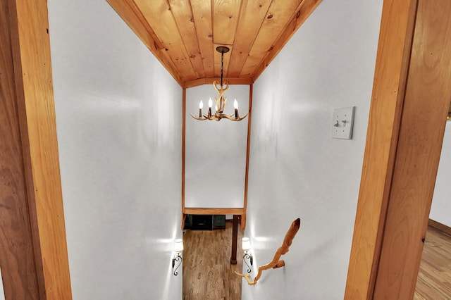 stairs featuring wood-type flooring, an inviting chandelier, and wood ceiling