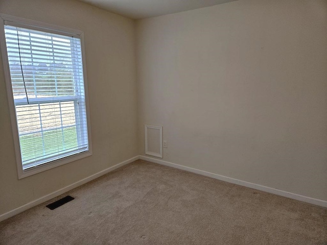 unfurnished room featuring light colored carpet, visible vents, and baseboards