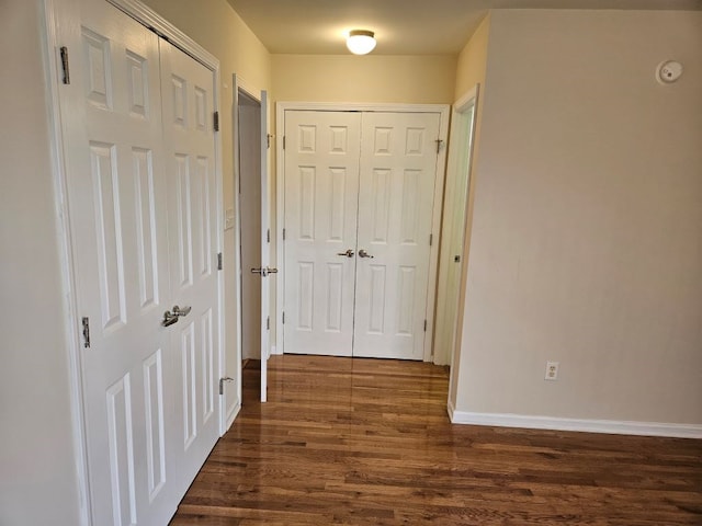 hall with dark wood-type flooring and baseboards