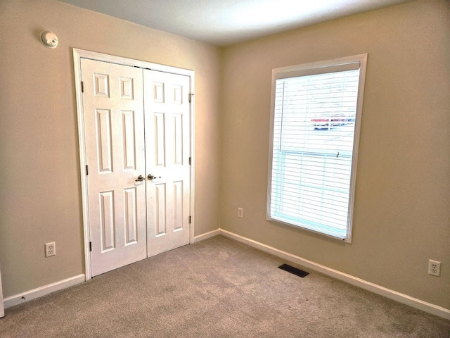 unfurnished bedroom with carpet floors, a closet, visible vents, and baseboards