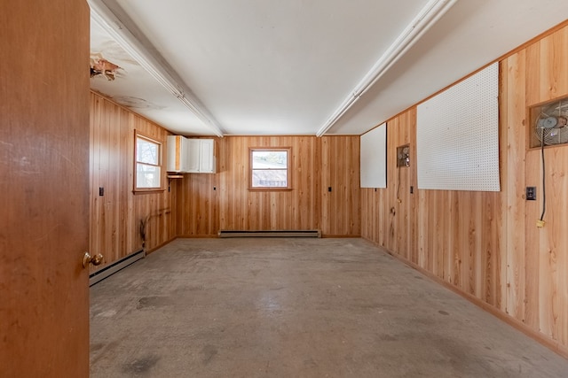 spare room featuring a baseboard heating unit and wood walls