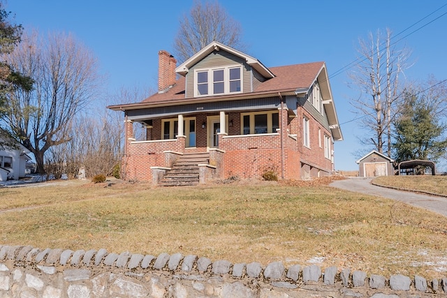 view of front of house with an outbuilding, a front yard, and covered porch