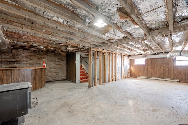 basement with a baseboard radiator and wooden walls