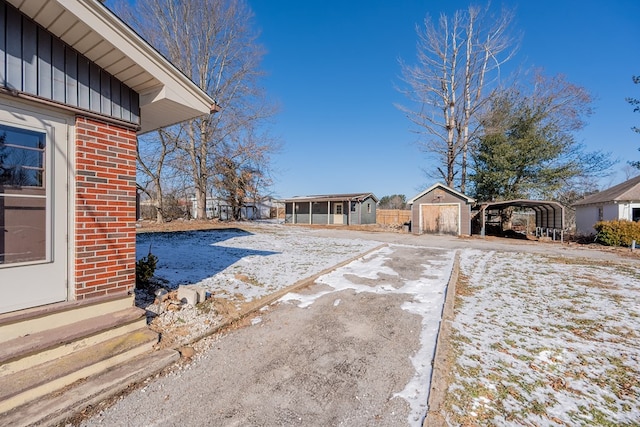 snowy yard with a storage shed and a carport