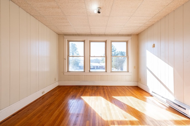 empty room featuring a baseboard heating unit and light hardwood / wood-style flooring