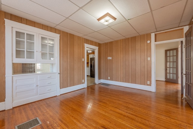 spare room featuring a paneled ceiling and light hardwood / wood-style flooring