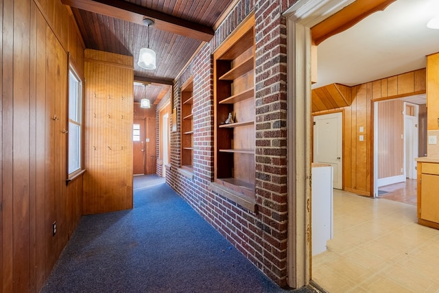 hall featuring beamed ceiling, brick wall, wooden walls, and built in features