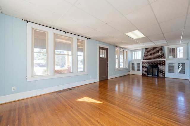 unfurnished living room with hardwood / wood-style flooring, a fireplace, and a drop ceiling