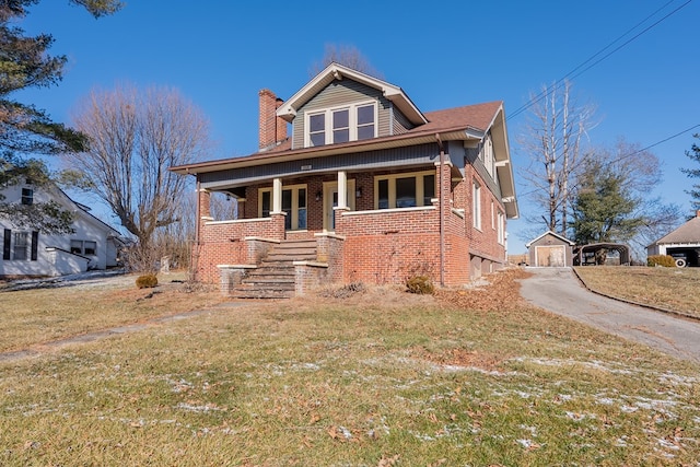 view of front of property with an outbuilding, a front yard, and covered porch