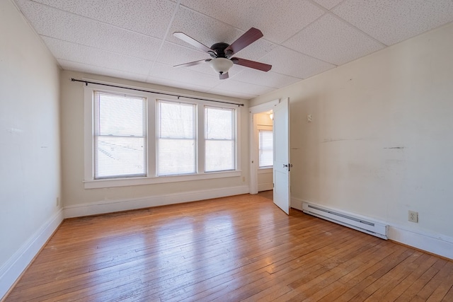 unfurnished room featuring plenty of natural light, light hardwood / wood-style floors, a drop ceiling, and a baseboard heating unit