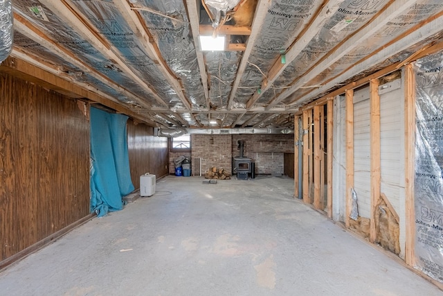 basement featuring wood walls and a wood stove