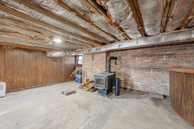 basement featuring a wood stove and wooden walls