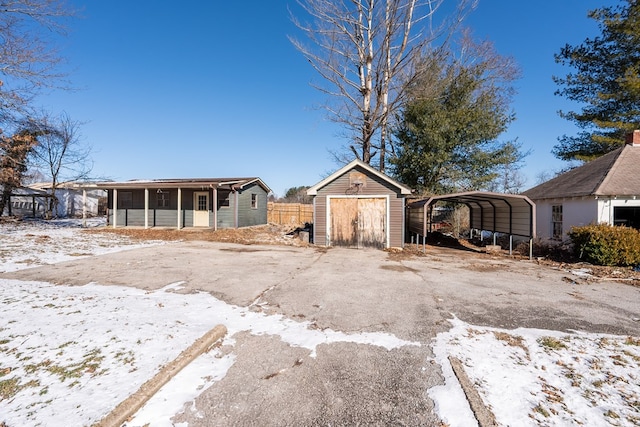 yard layered in snow with a carport and a storage unit