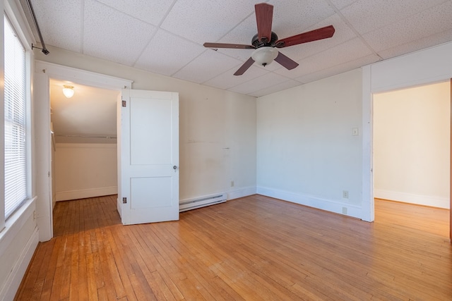 spare room featuring baseboard heating, a paneled ceiling, ceiling fan, and light wood-type flooring