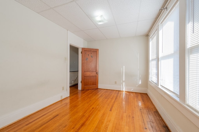 unfurnished room featuring hardwood / wood-style flooring and a drop ceiling