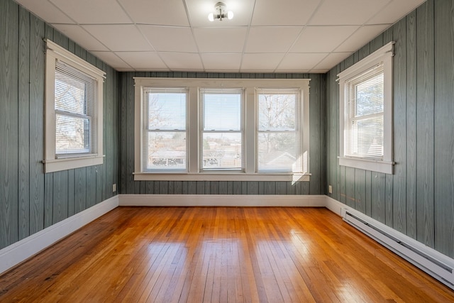 unfurnished sunroom with a drop ceiling and a baseboard heating unit