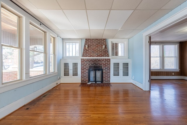 unfurnished living room with a drop ceiling, dark wood-type flooring, and a fireplace