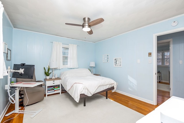 bedroom with ceiling fan, ornamental molding, and light wood-type flooring