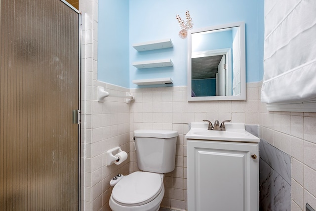 bathroom with vanity, toilet, an enclosed shower, and tile walls