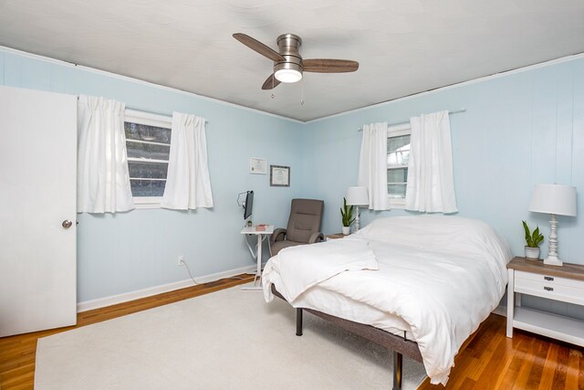 bedroom with dark wood-type flooring, ceiling fan, and crown molding