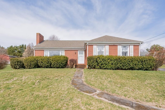 view of front of property featuring a chimney, brick siding, and a front lawn