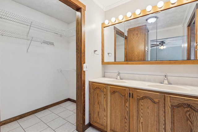 bathroom with a textured ceiling, a spacious closet, ornamental molding, and a sink